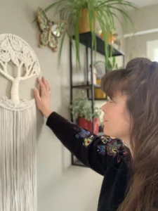 Amandine regarde et touche un arbre de vie blanc accroché au mur