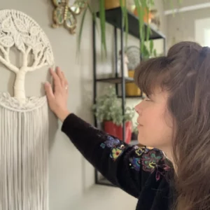 Amandine regarde et touche un arbre de vie blanc accroché au mur