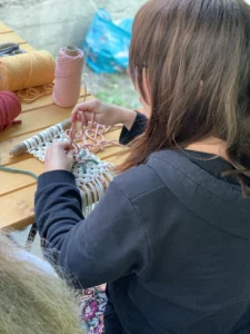 Femme vue de dos qui tisse un macramé