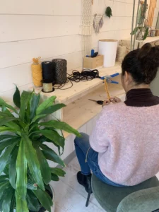 Participante qui tisse un macramé porte-plante dans l'atelier d'Ambellire